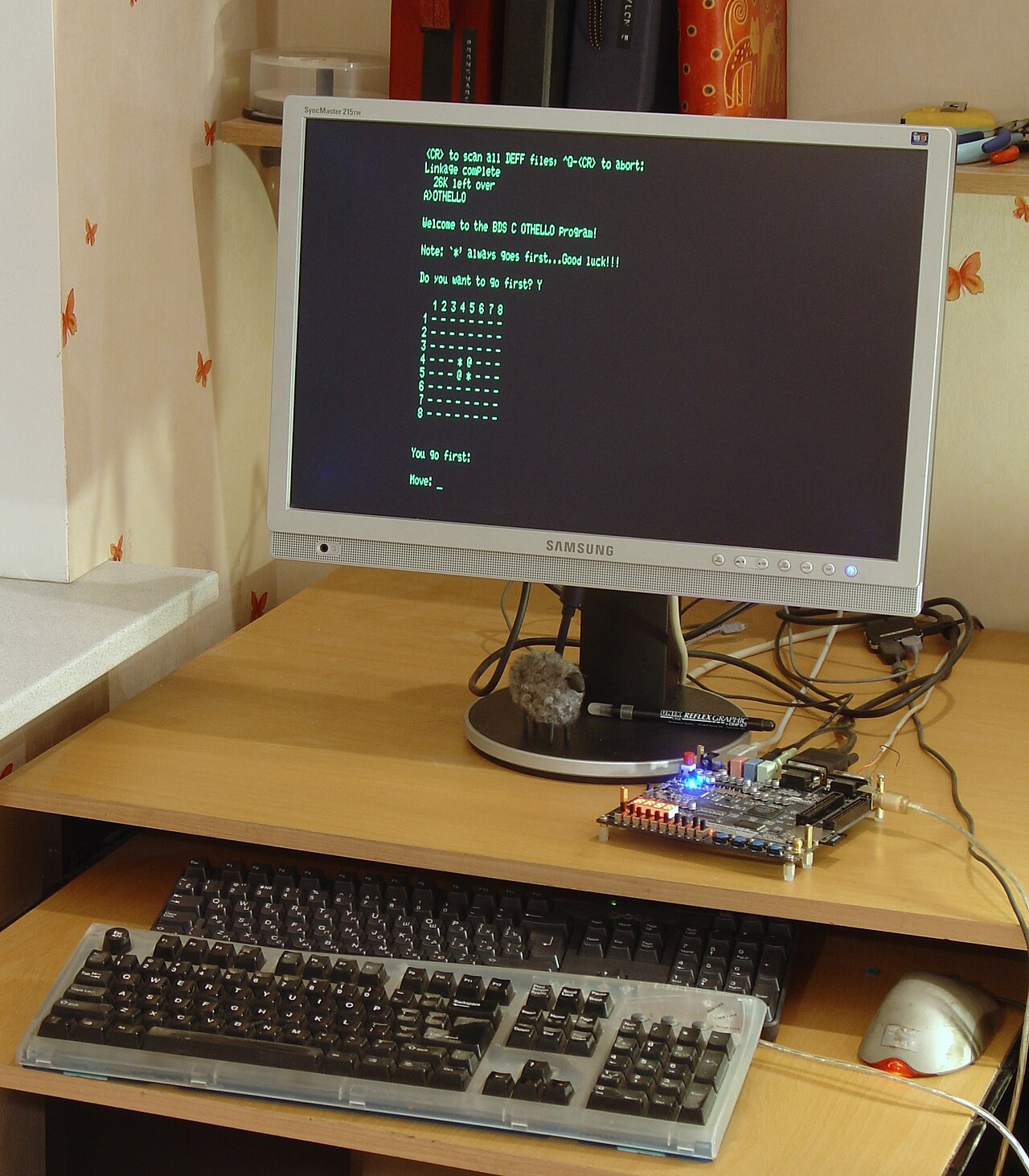 An FPGA development board on a desk running retro computing software on a monitor