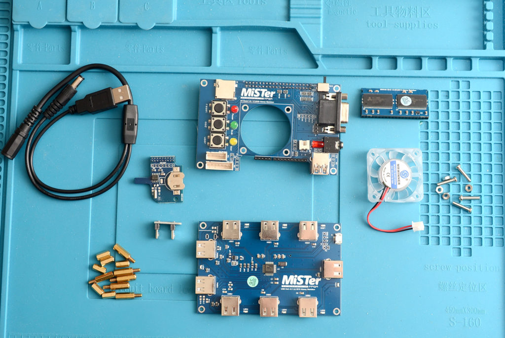 A MiSTer FPGA build laid out on a work mat, showing the I/O board, USB hub board and the essential 128MB SDRAM module