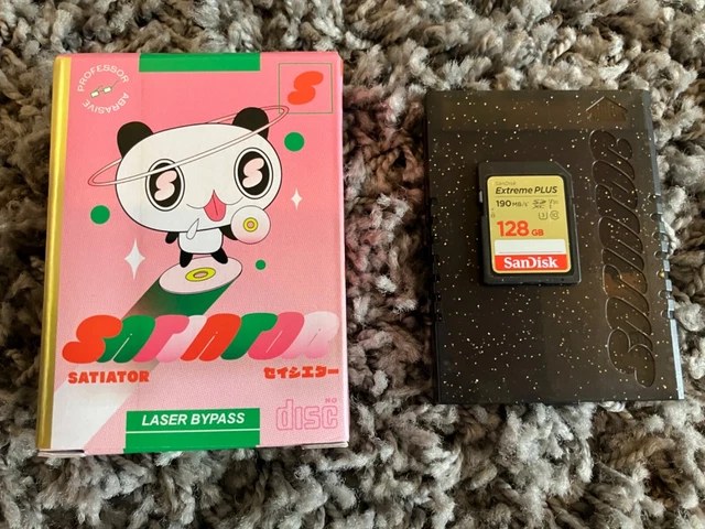 The Satiator ODE for Sega Saturn with its retail box and a 128GB SD card resting in its cartridge case
